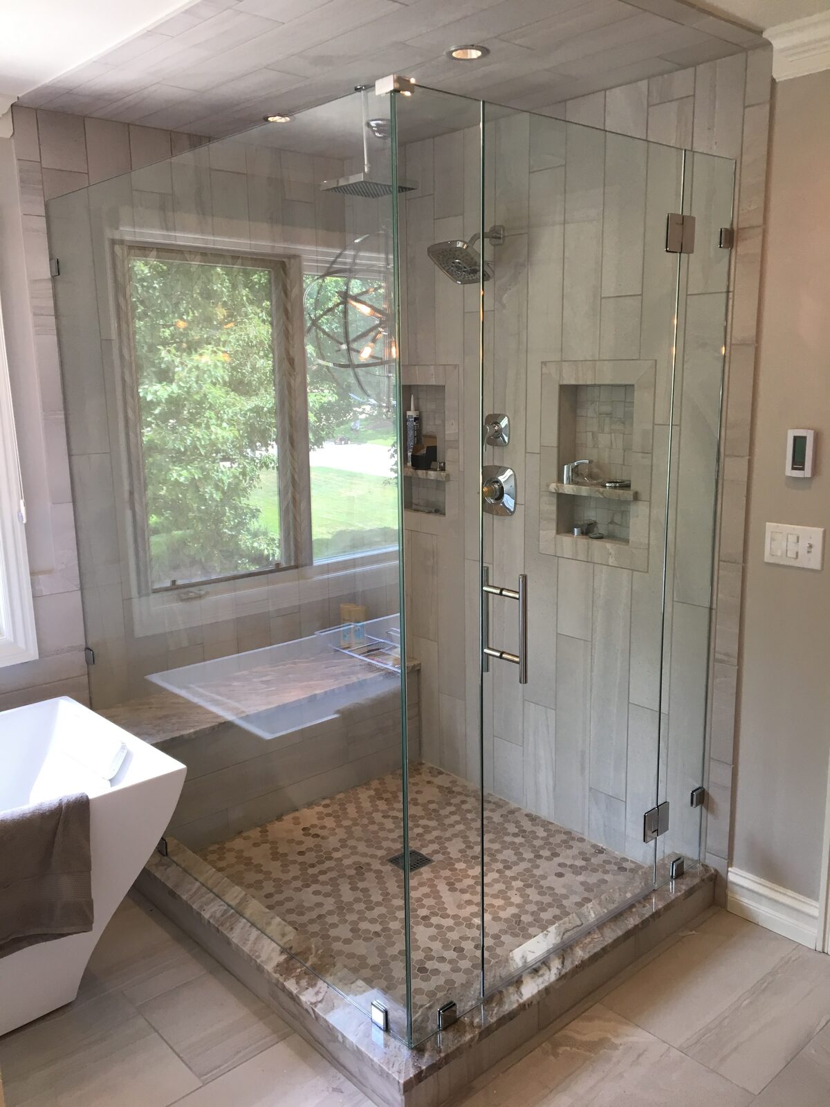 Frameless corner glass shower with travertine and tub