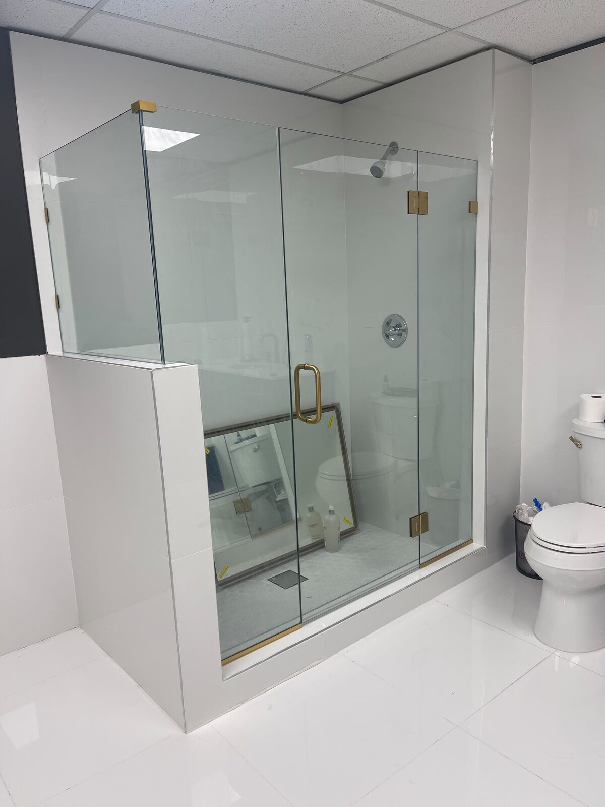 Frameless glass shower with gold hardware and white marble