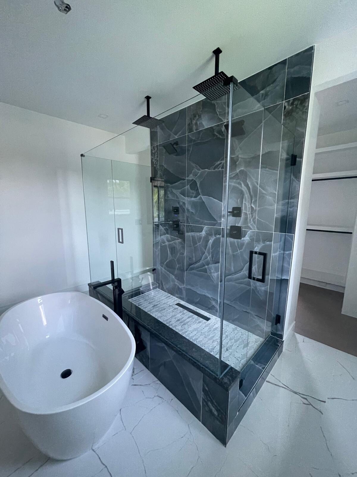 Frameless glass shower with blue onyx and freestanding tub