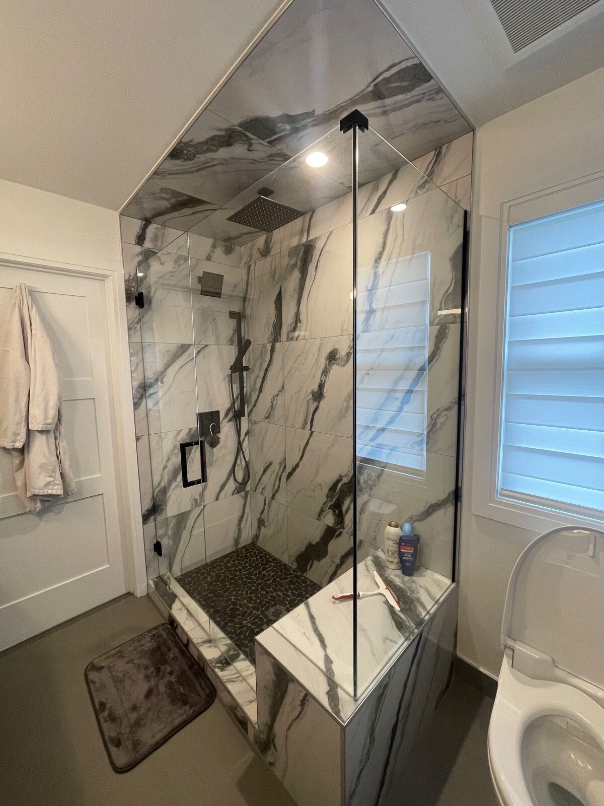 Frameless glass shower enclosure on bookmatched marble with a built-in bench