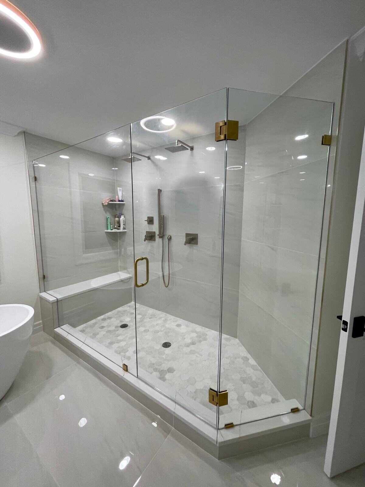 Frameless glass shower with bench and gold hardware