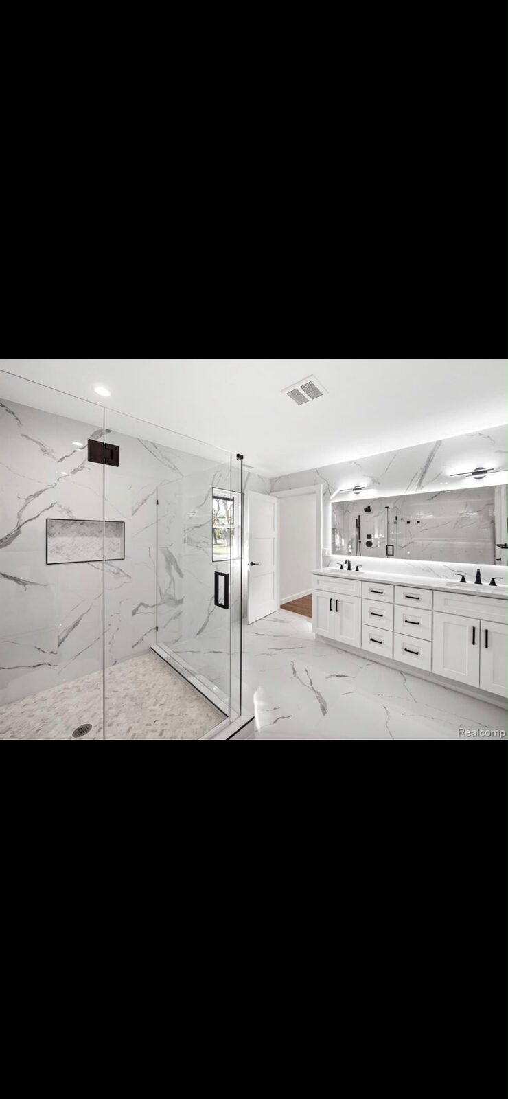 Frameless glass shower with white marble and double vanity
