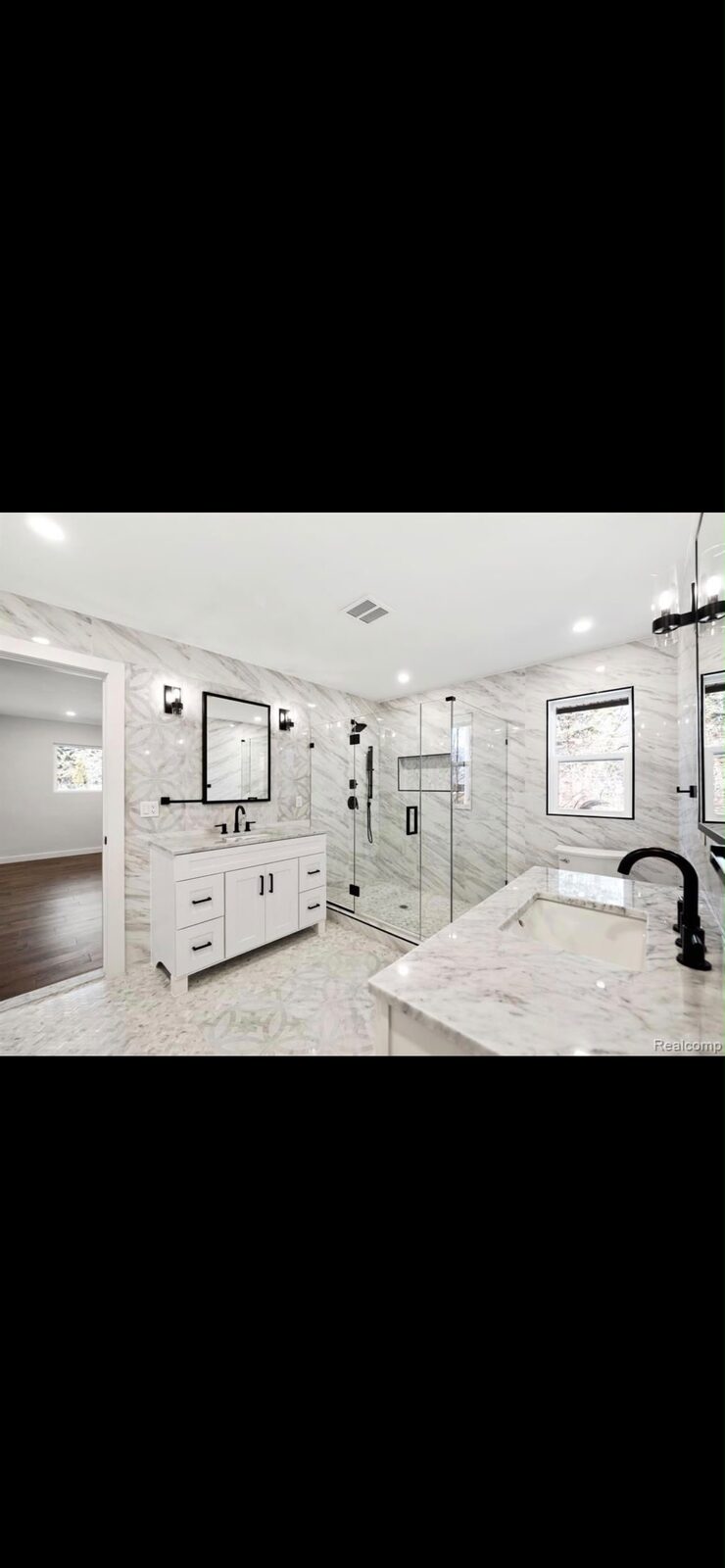 Frameless glass shower in a white marble bathroom