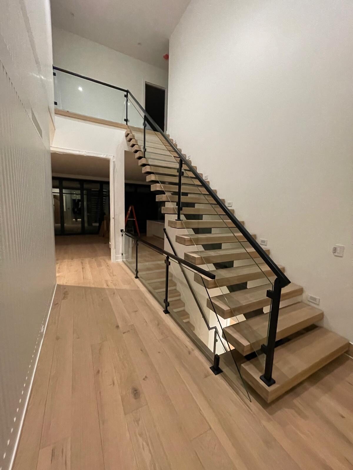Floating staircase with glass railing in a hallway